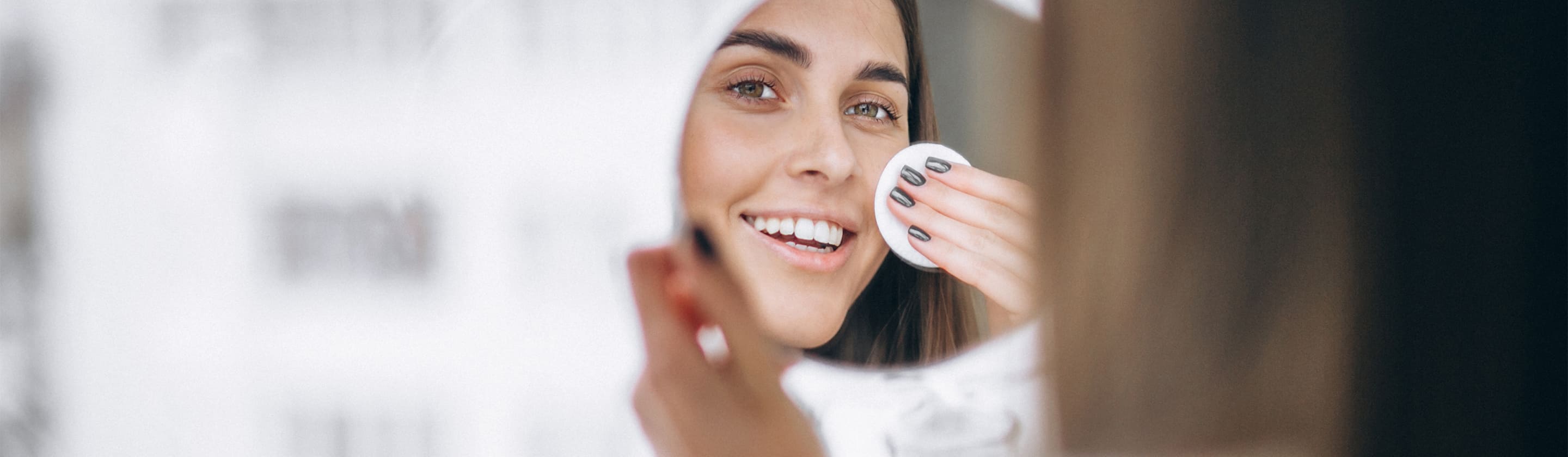 A woman with uneven skin tone looking into the mirror